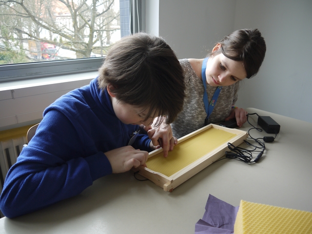 Felix zeigt Celine, einer Schülerin der Biesalski-Schule, wie man Mittelwände in die Rähmchen einlötet